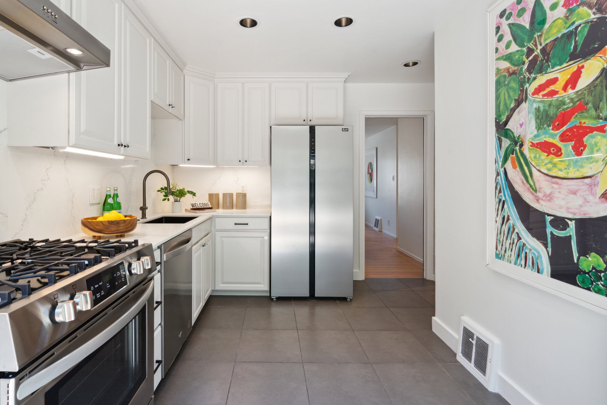 A lightly colored and updated kitchen with new quartz counters and backsplash and stainless appliances