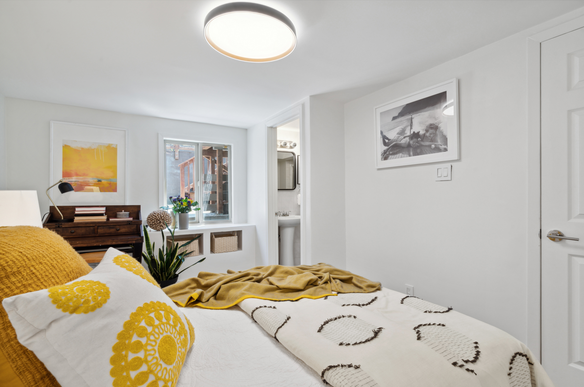 The lower bedroom with a king-sized bed and LED light overhead, carpeted floors below