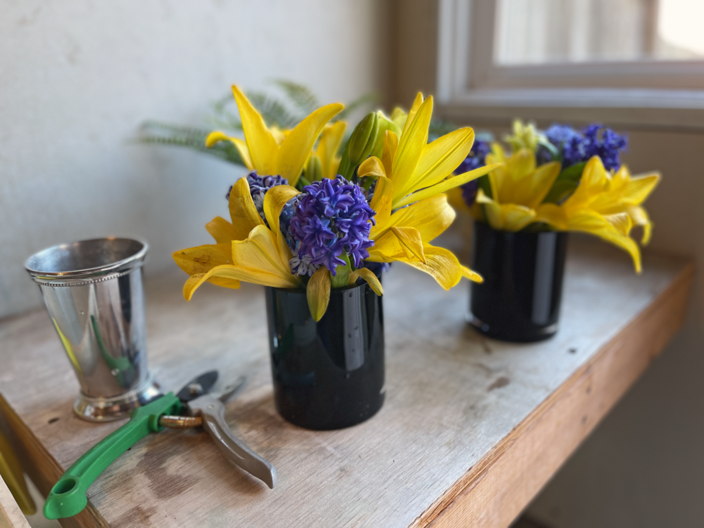 fresh cut flowers Fresh yellow lilies and purple hyacinths arranged in black vases, placed on a rustic wooden table beside gardening shears, part of custom floral arrangements by Kevin add the finishing touches to home staging