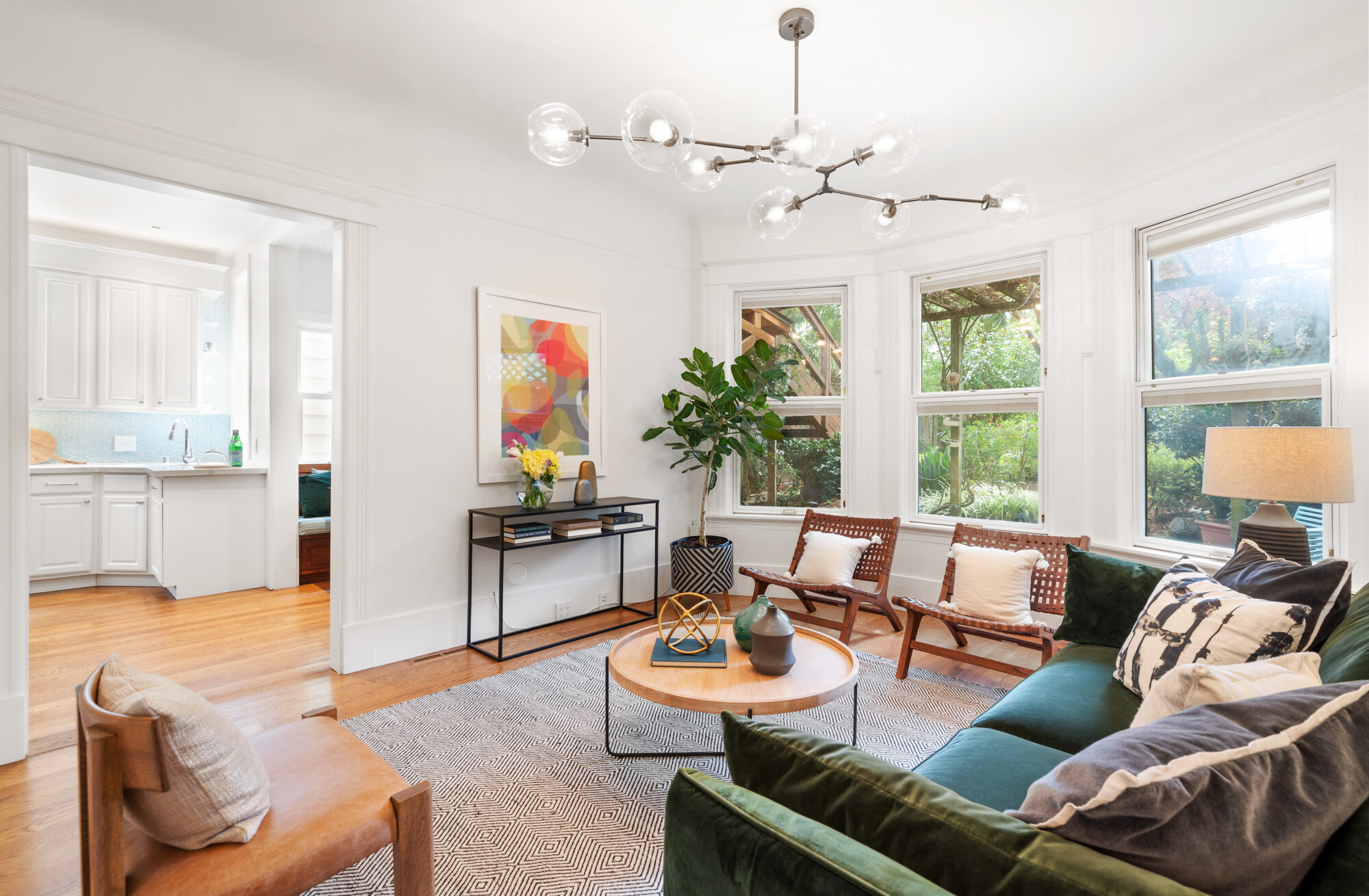 _DSC9301 omfortably elegant living room featuring large bay windows, sophisticated decor, designer chandelier, and greenery views.”