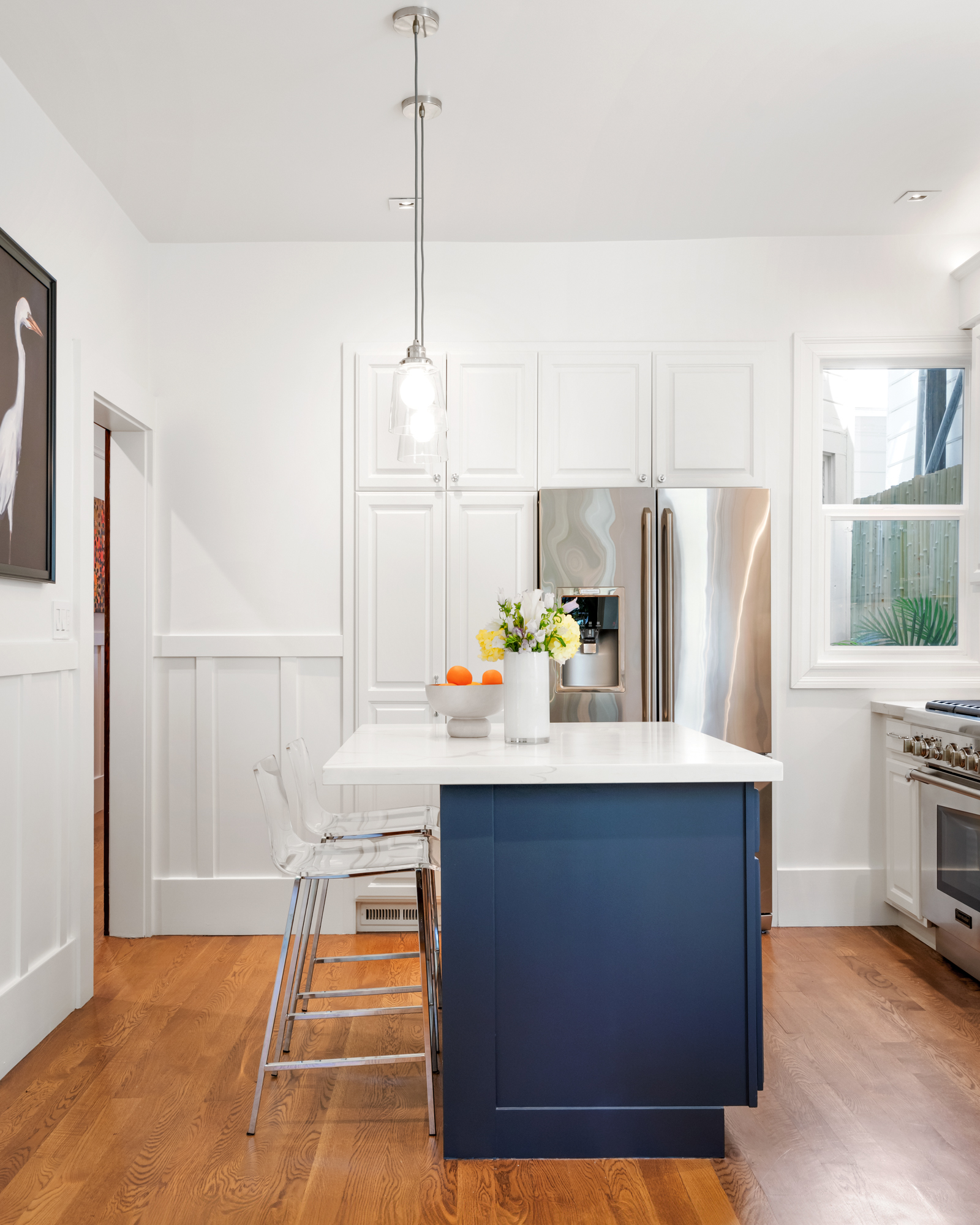 Contemporary kitchen with quartz-topped island, stainless appliances, pendant lights, designer backsplash, and adjacent dining area with garden views.”