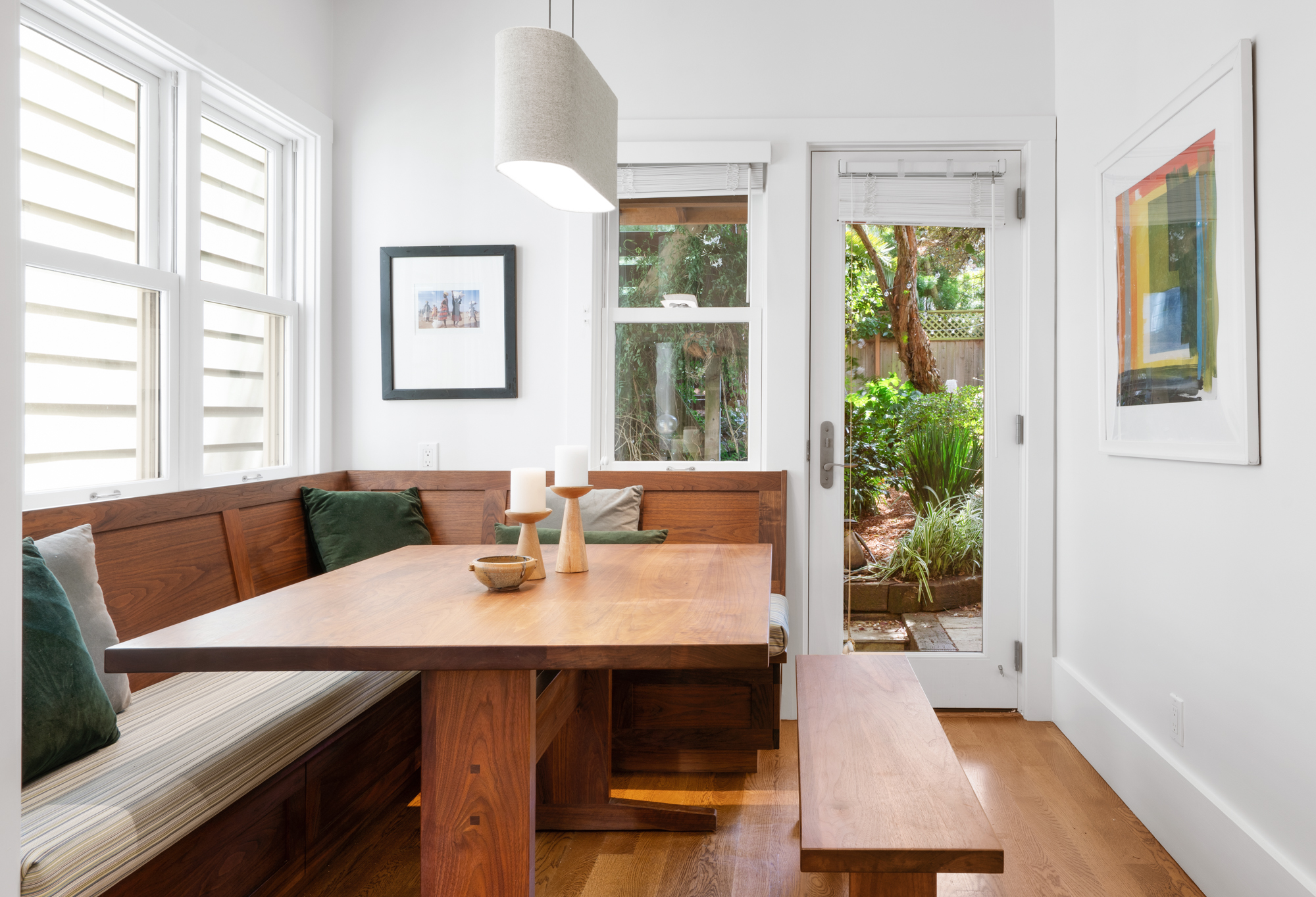Dining nook featuring custom walnut table and bench seating, garden access, and abundant natural light.