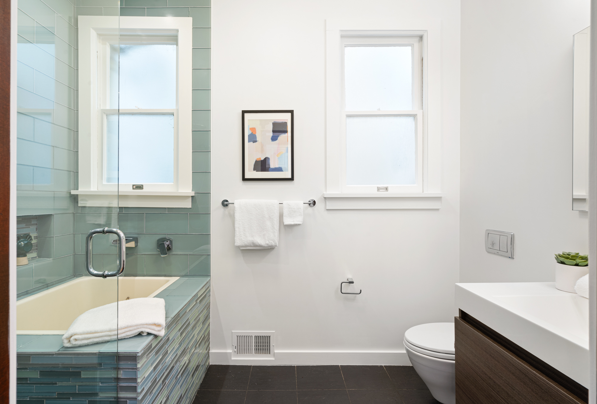 Modern bathroom featuring soaking tub, glass-tile surround, glass partition, contemporary fixtures.