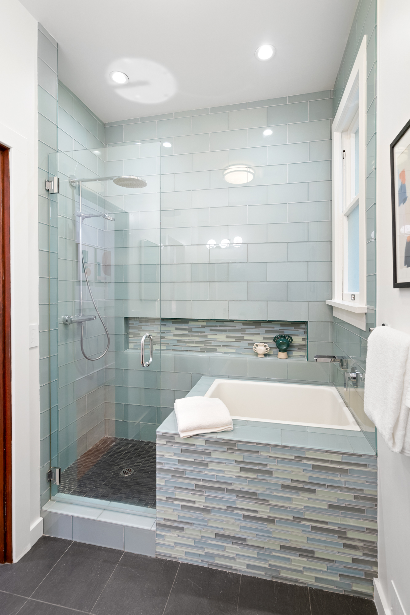Modern bathroom featuring soaking tub, glass-tile surround, glass partition, contemporary fixtures