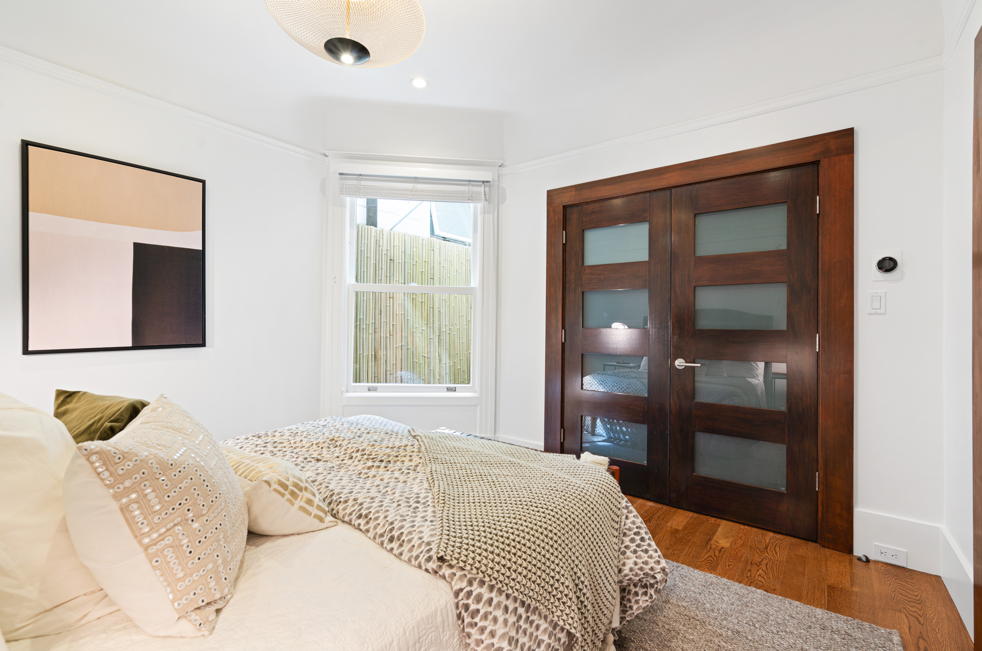 Contemporary bedroom with striking pendant lamp, frosted glass doors, and sophisticated decor accents.