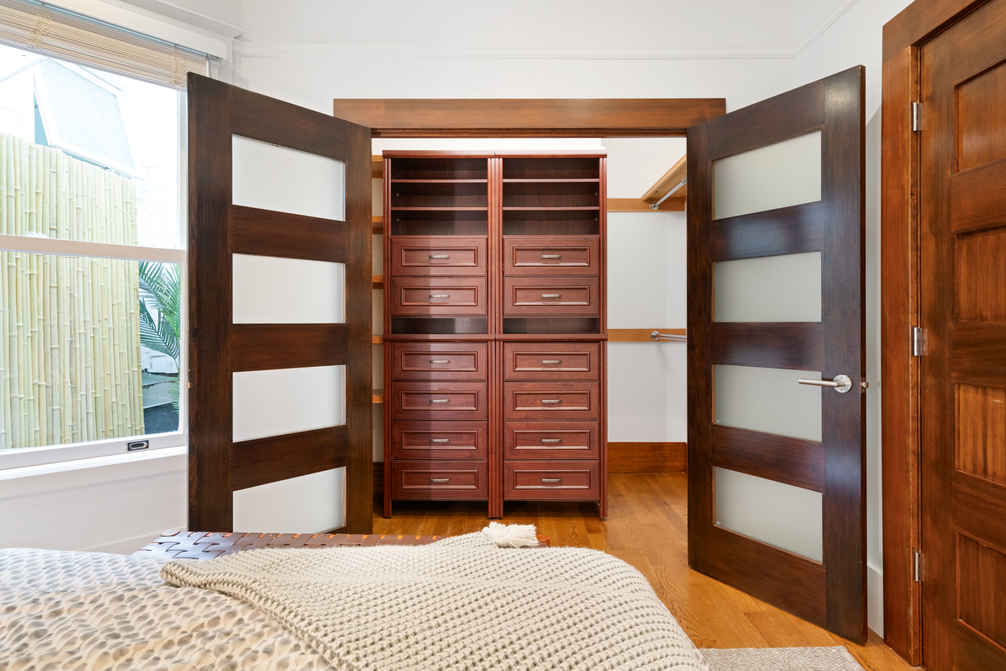 Contemporary bedroom with striking pendant lamp, frosted glass doors, and sophisticated decor accents.