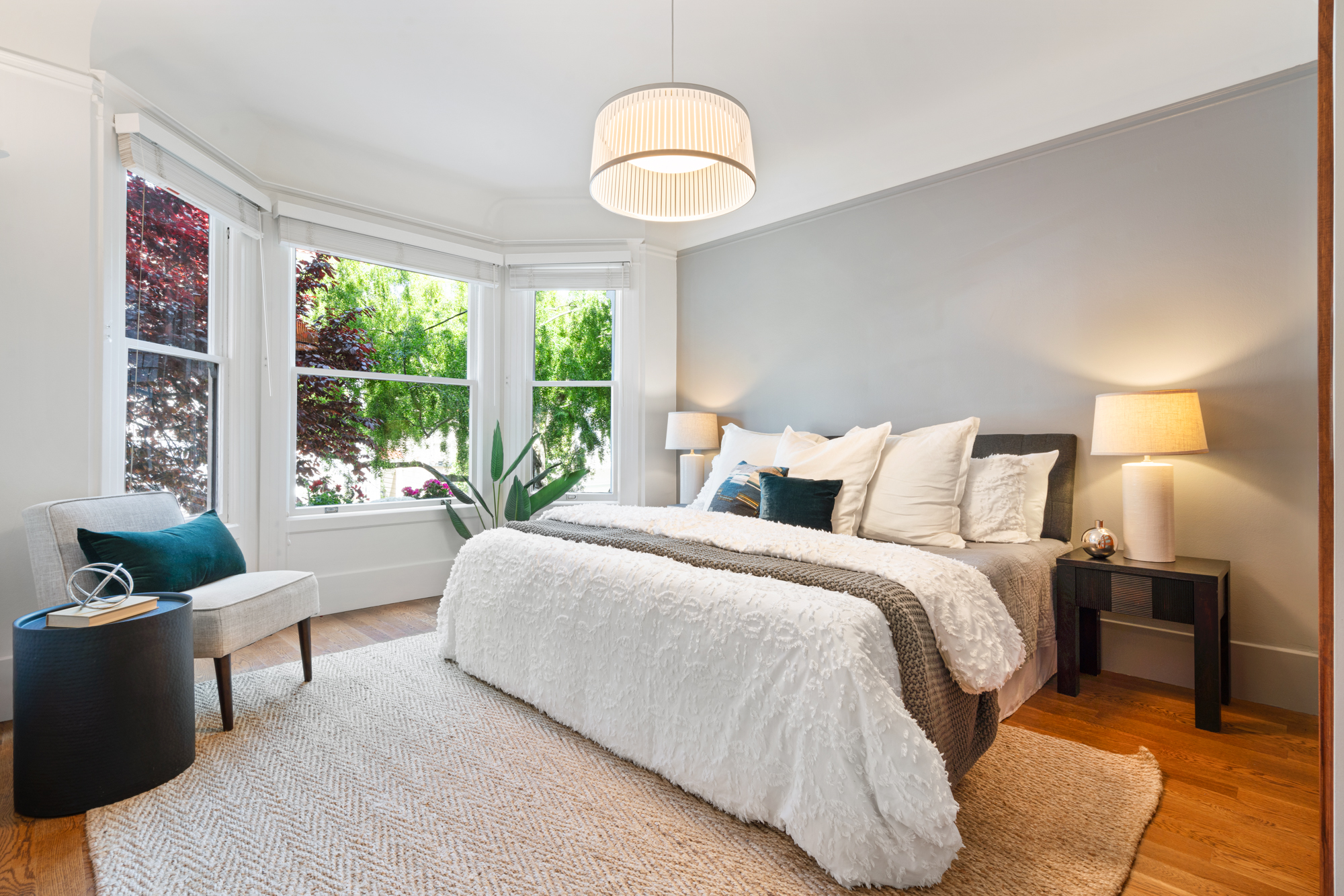 Peaceful bedroom with contemporary decor, cozy textiles, designer lighting, and large window providing natural light.