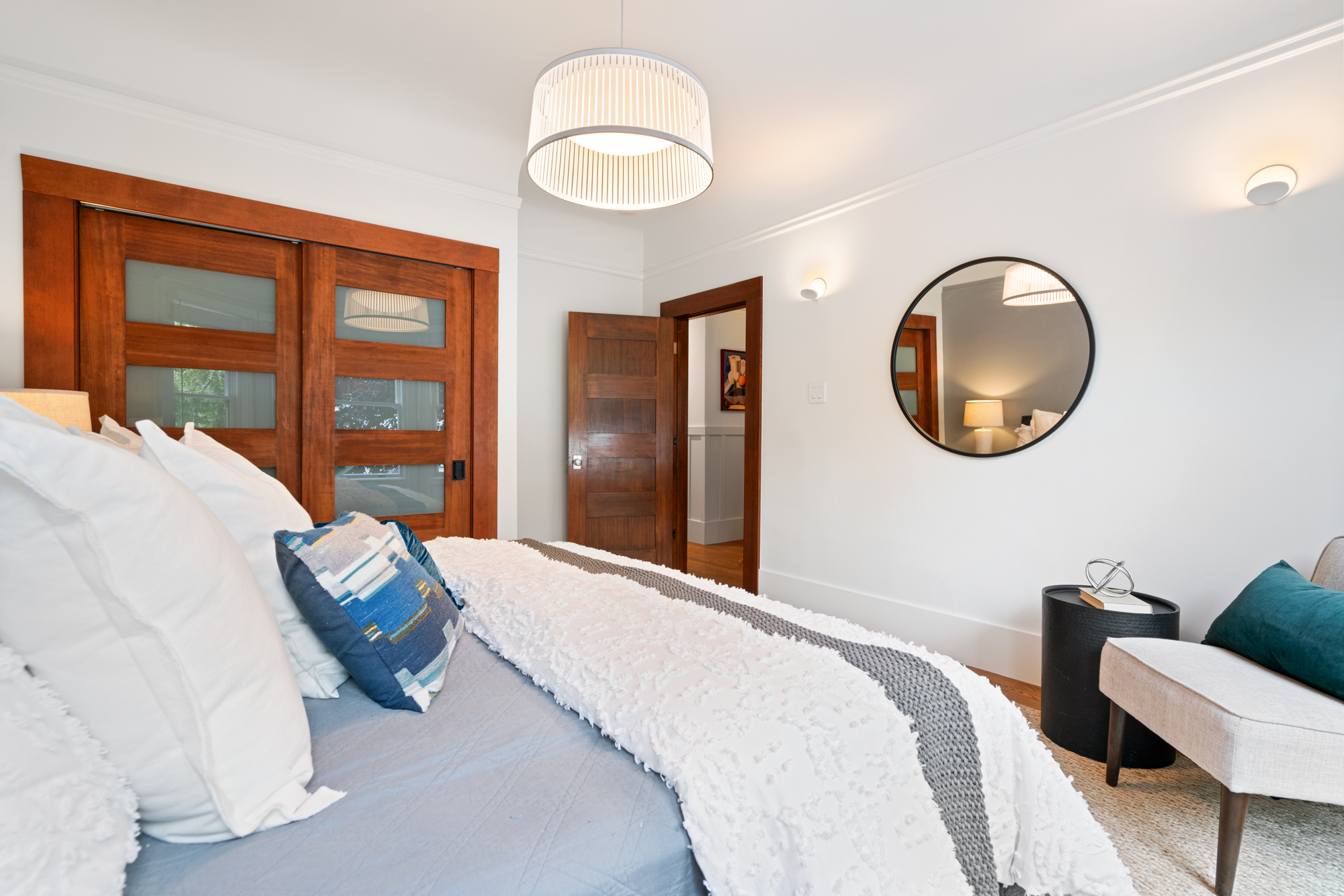 Bright bedroom with hardwood floors, contemporary pendant lighting, frosted glass double doors revealing a large closet.