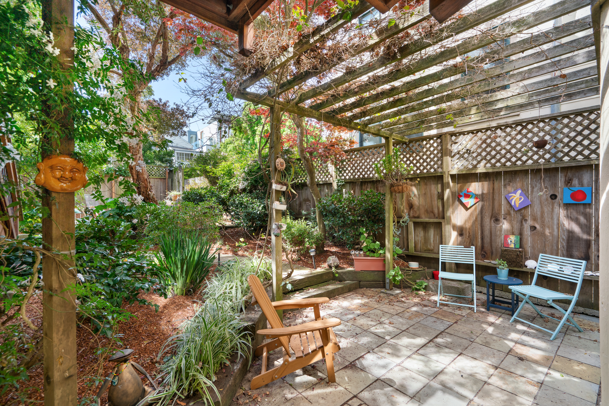 Private garden oasis with flagstone patio, lush greenery, string lights, and comfortable seating areas.