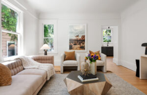 Living room with modern furniture, layered textures, and natural light from tall windows.