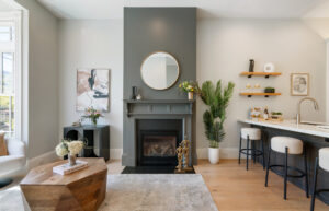 . Living room with modern fireplace, round mirror, and open kitchen with bar seating at 1221 San Bruno, San Francisco.